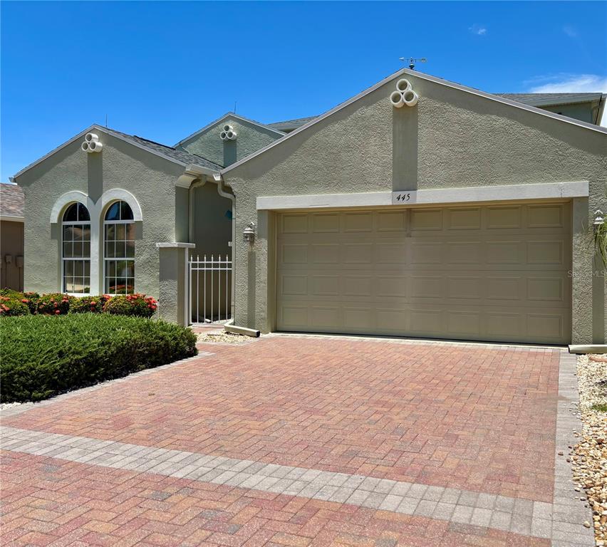 A dining area and living room with tile floors, neutral furniture, and large shuttered windows — 445 NOBLE FAIRE DRIVE, SUN CITY CENTER, FL