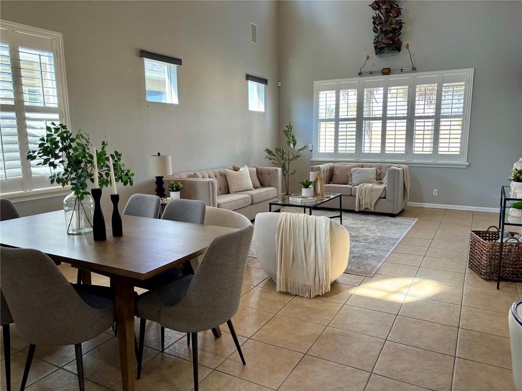 A dining area with a wooden table and chairs opens to a living room and kitchen — 445 NOBLE FAIRE DRIVE, SUN CITY CENTER, FL