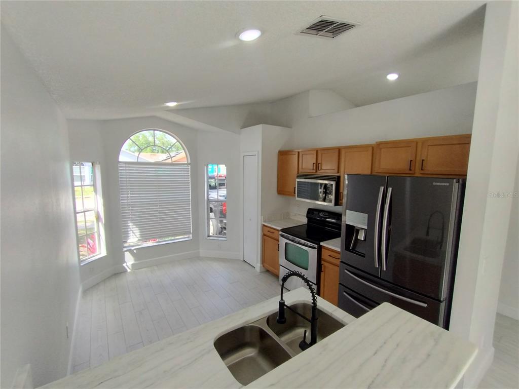 A kitchen with light wood cabinets, stainless steel appliances, and a marble-look island countertop — 1716 CHATHAM CIRCLE, APOPKA, FL