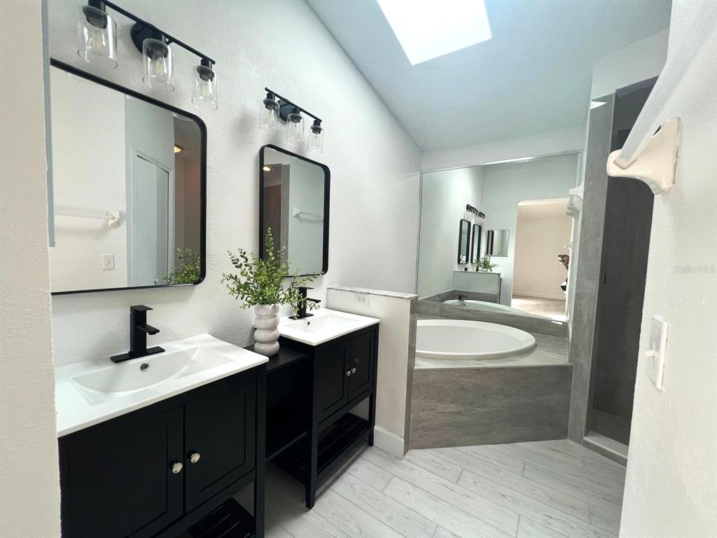 A bathroom features dual black vanities, rectangular mirrors, a soaking tub, and a walk-in shower — 1716 CHATHAM CIRCLE, APOPKA, FL