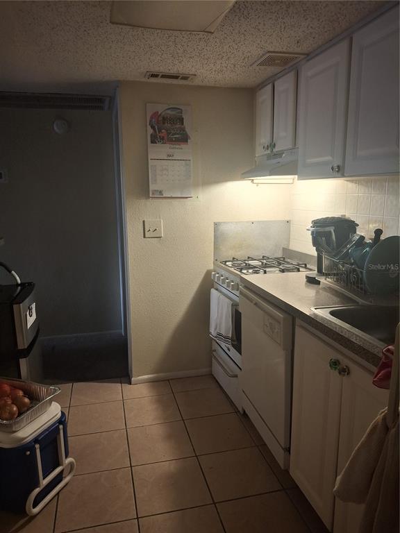 A small kitchen features white cabinets, a gas stove, a dishwasher, and tiled flooring — 151 OYSTER BAY CIRCLE UNIT 300, ALTAMONTE SPRINGS, FL