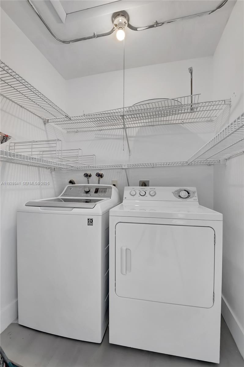 A laundry closet features a white top-load washer and dryer beneath wire shelving — 708 Normandy O # 708, Delray Beach FL 33484, DELRAY BEACH, FL