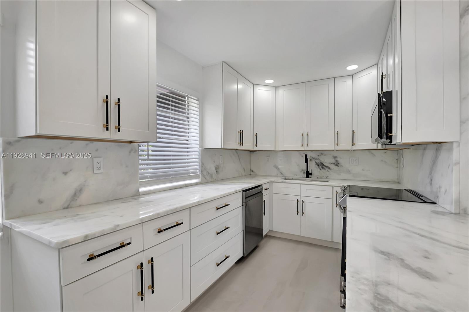 A modern kitchen features white shaker cabinets, marble countertops, and a matching marble backsplash — 708 Normandy O # 708, Delray Beach FL 33484, DELRAY BEACH, FL
