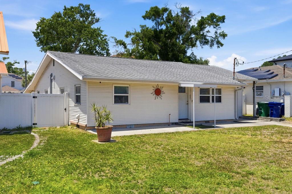 A single-story house with light-colored siding, a gray shingled roof, and a concrete patio — 7207 S WEST SHORE BOULEVARD, TAMPA, FL