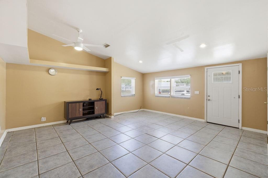 A living room with tan walls, tile flooring, a ceiling fan, and a front door — 7207 S WEST SHORE BOULEVARD, TAMPA, FL