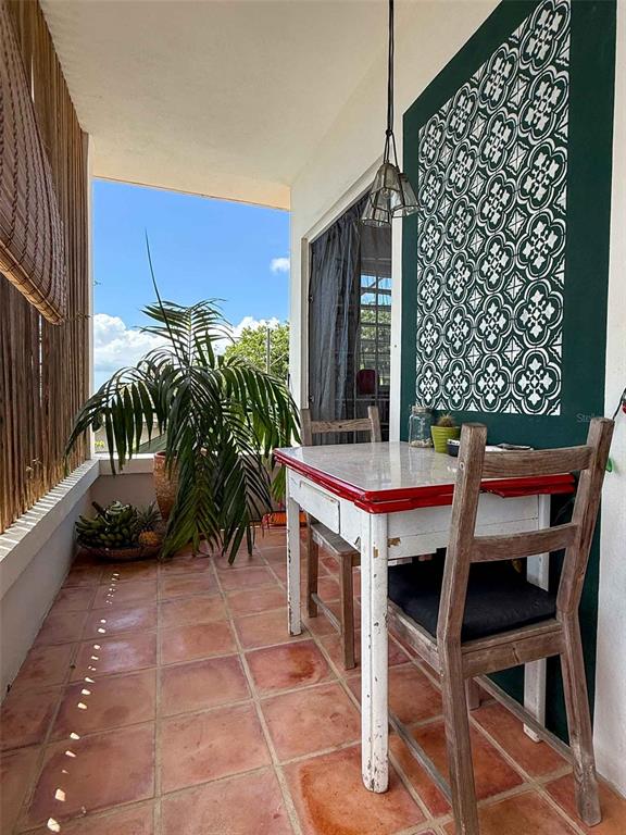A covered balcony features a small table with a red rim, chairs, and patterned wall decor — 213 CALLE IGLESIAS, VIEQUES, PR