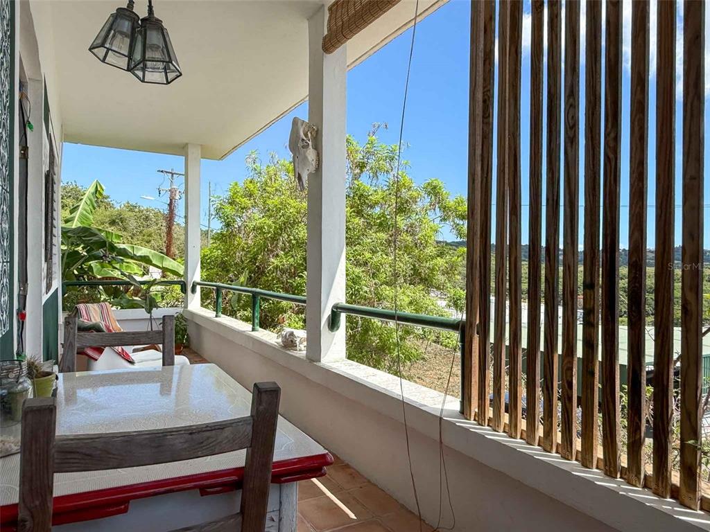 A covered balcony features a dining table, wooden chairs, and a slatted privacy screen — 213 CALLE IGLESIAS, VIEQUES, PR