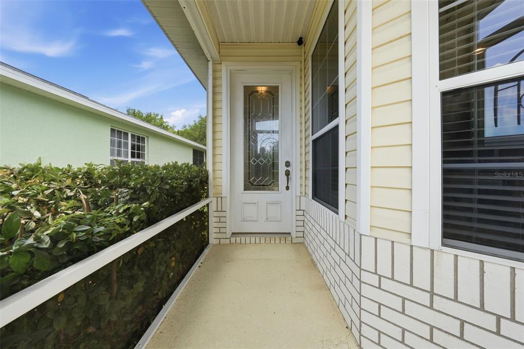 A concrete walkway leads to a screened-in front porch with light yellow siding — 4962 RAINBOW TROUT ROAD, TAVARES, FL