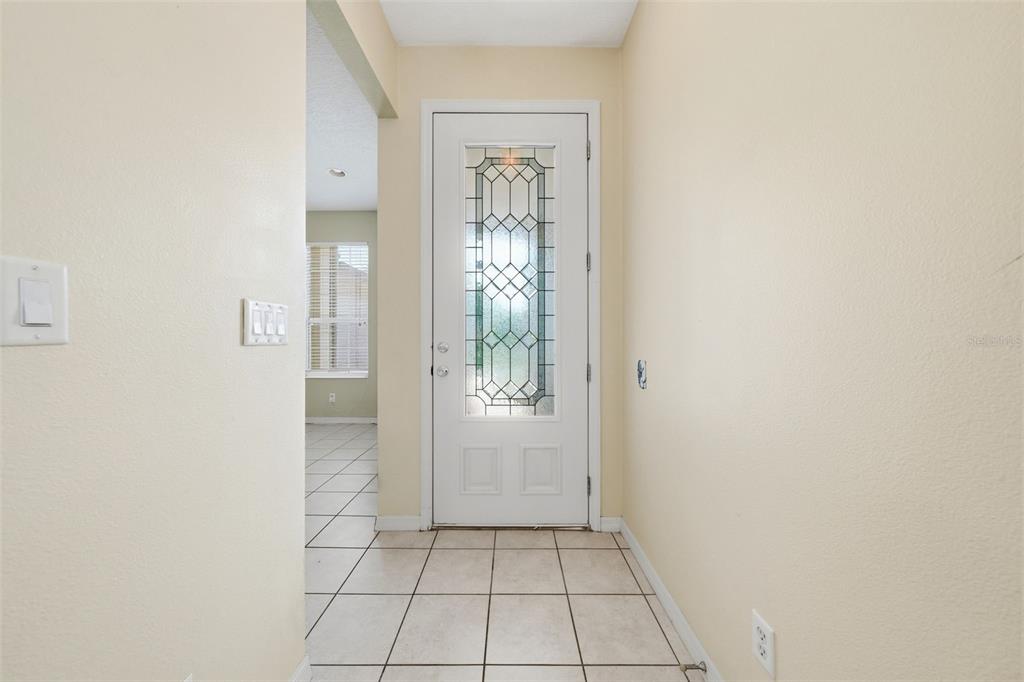 A covered entryway features a white front door with a glass insert and brick siding — 4962 RAINBOW TROUT ROAD, TAVARES, FL