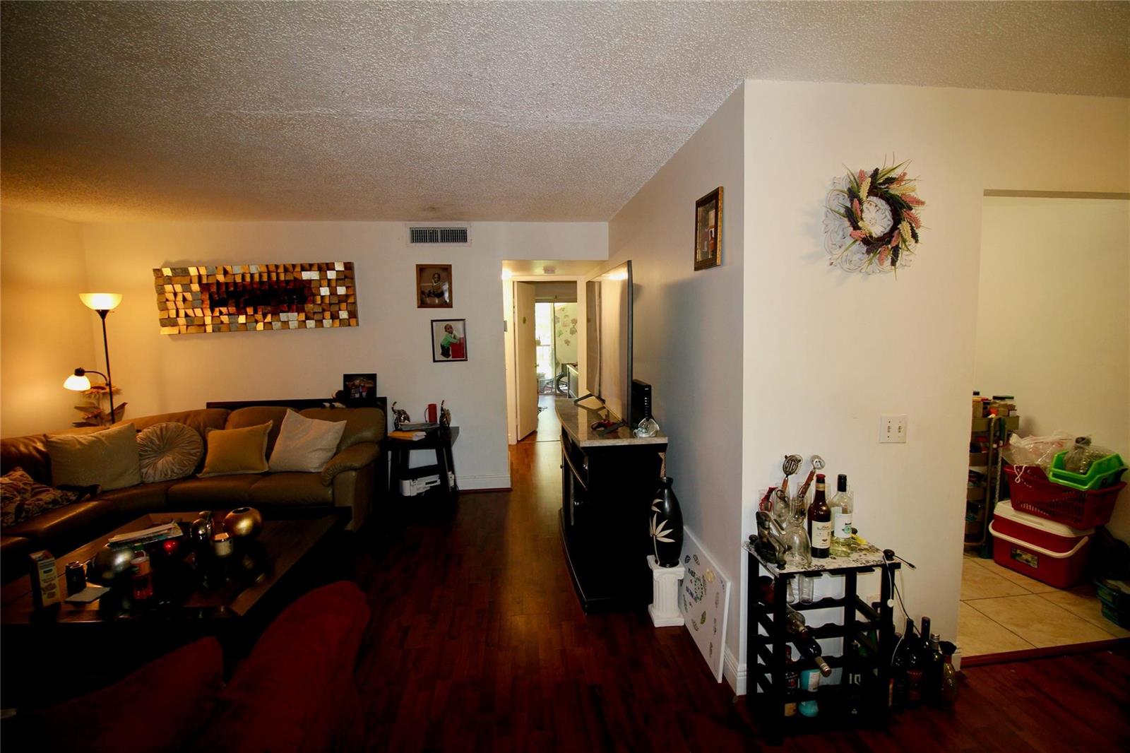 A living room with dark wood flooring, a leather sofa, and a hallway leading through — 316 Meadows Circle # 316, Boynton Beach FL 33436, BOYNTON BEACH, FL