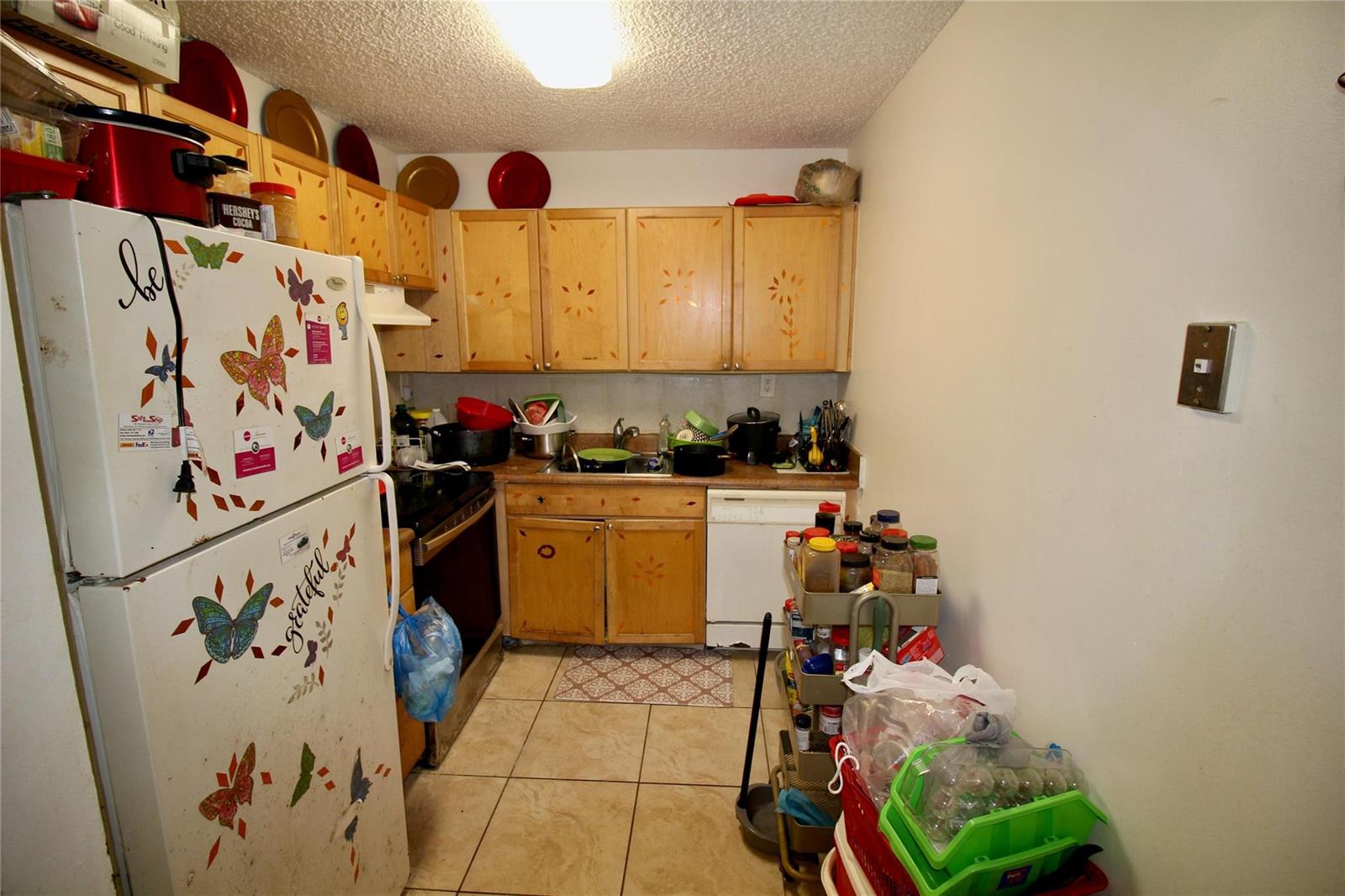 A small kitchen features light wood cabinets, tiled floors, a white refrigerator, and a utility cart — 316 Meadows Circle # 316, Boynton Beach FL 33436, BOYNTON BEACH, FL