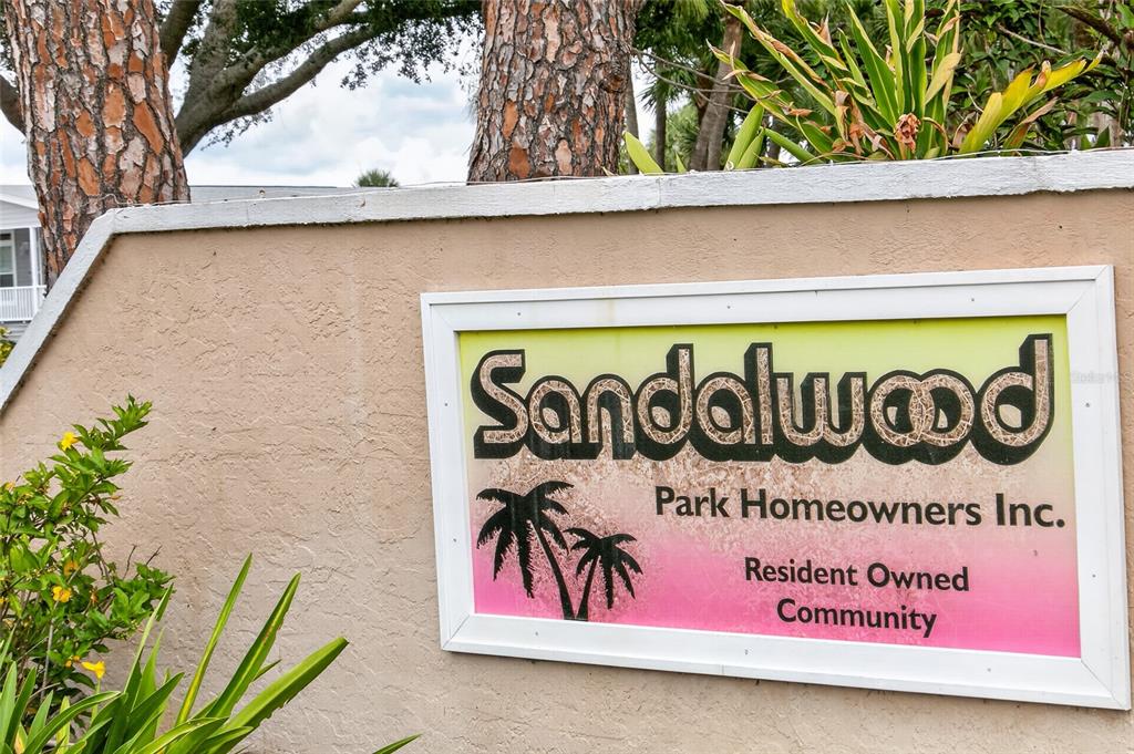 A sign for Sandalwood Park Homeowners Inc. is mounted on a tan stucco wall — 498 LONGWOOD DRIVE, VENICE, FL