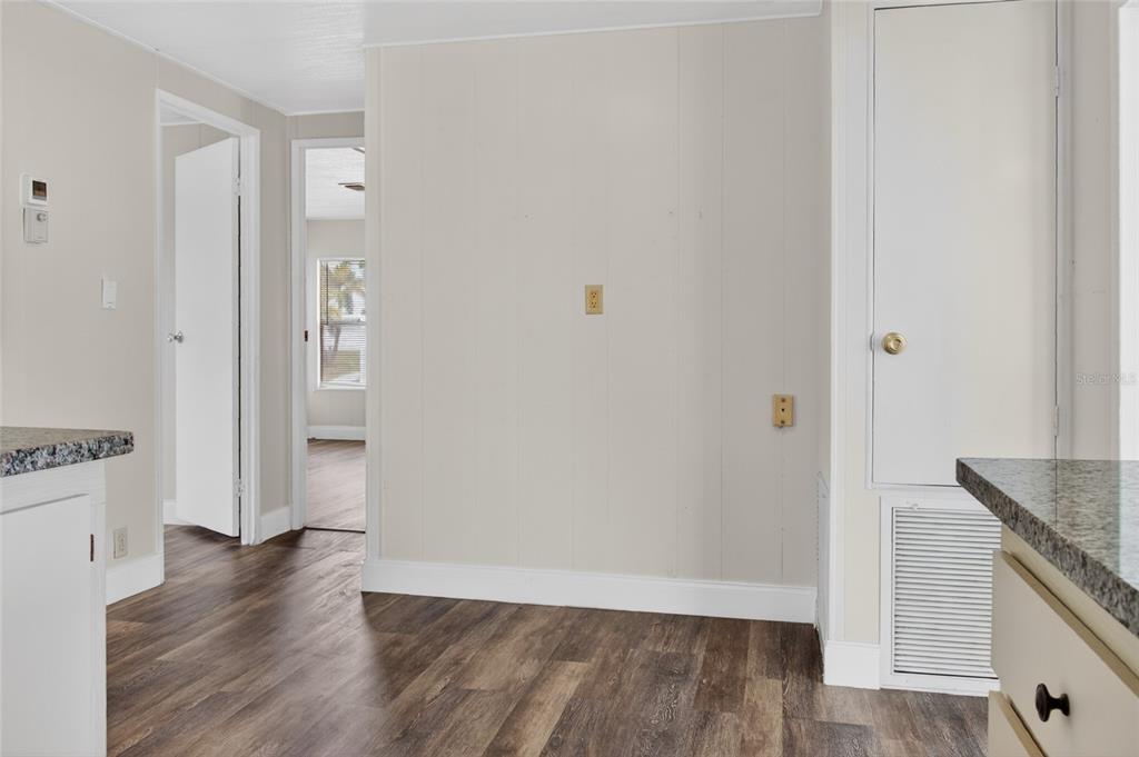 A kitchen area with wood-look flooring, paneled walls, and a doorway leading to another room — 498 LONGWOOD DRIVE, VENICE, FL