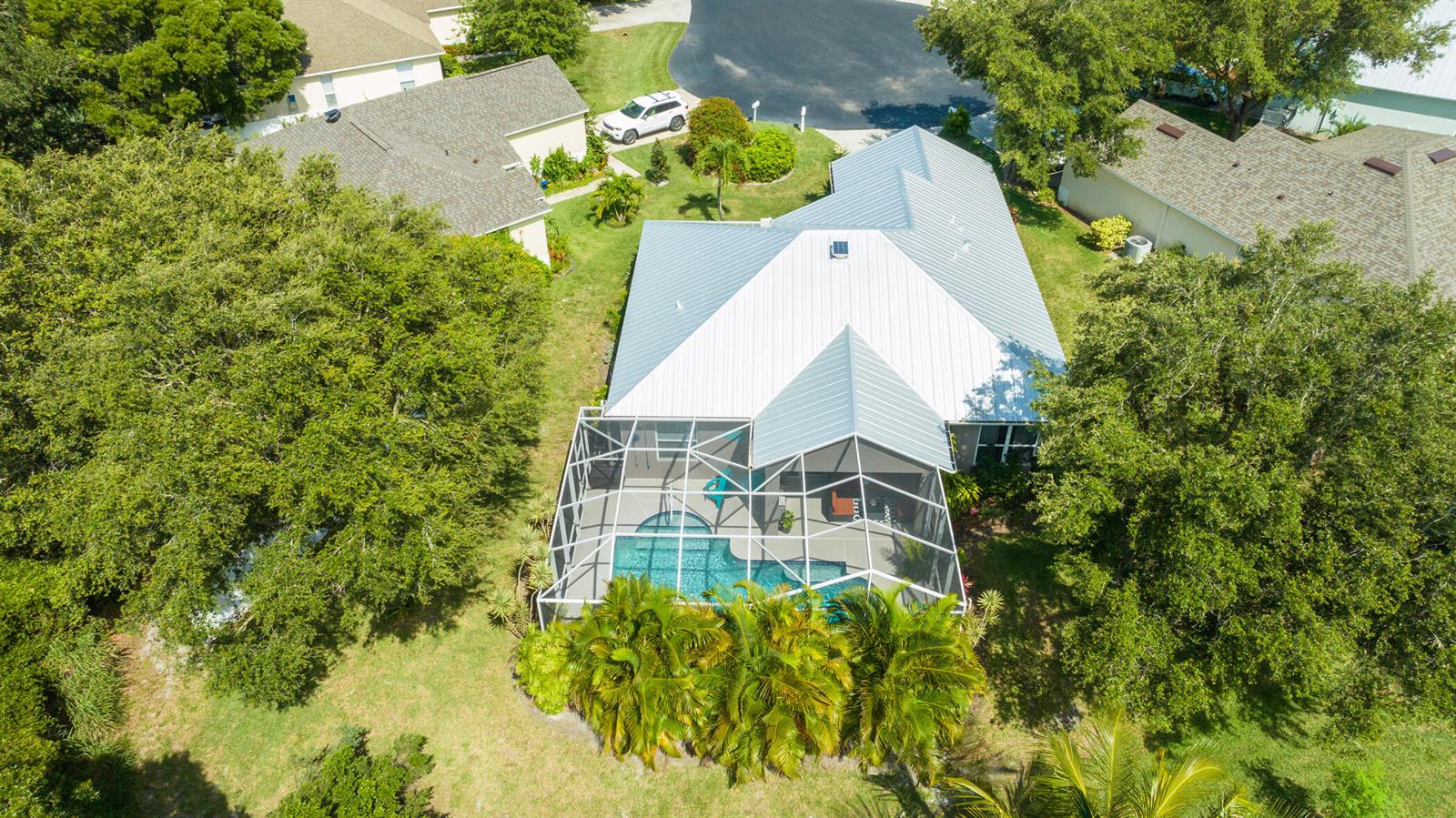 An aerial view of a house with a metal roof and a screened-in pool area — SEBASTIAN, FL