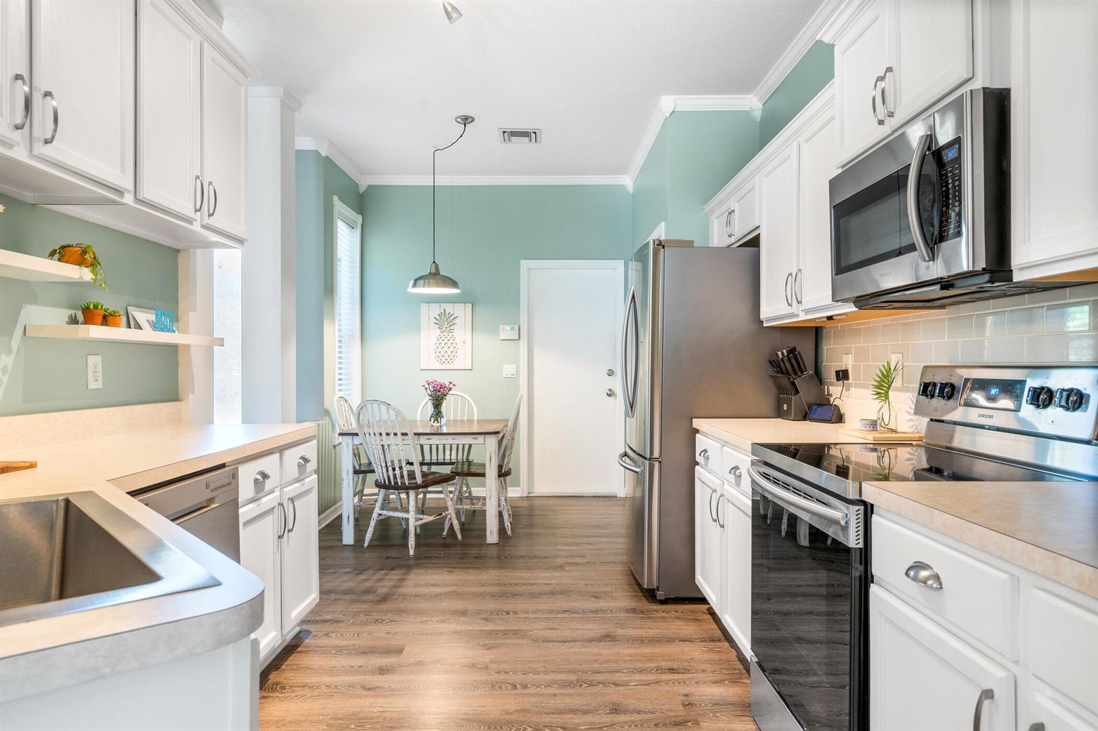 A kitchen with white cabinets, stainless steel appliances, and a dining area with a table — SEBASTIAN, FL