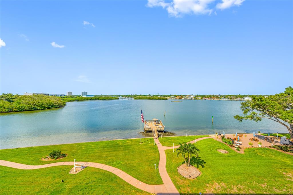 An elevated view of a grassy lawn, a wooden dock with a flag, and a bay — 1847 SHORE DRIVE S UNIT 509, ST PETERSBURG, FL