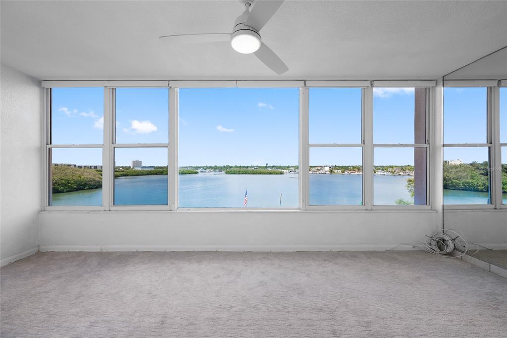 An empty room with beige carpet, a ceiling fan, and large windows overlooking a bay — 1847 SHORE DRIVE S UNIT 509, ST PETERSBURG, FL