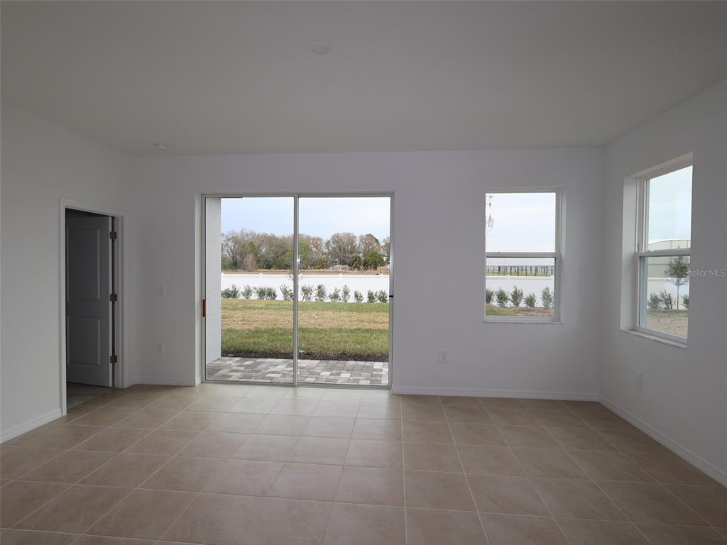 An empty room with tile flooring, a sliding glass door, and two windows — 4520 OUTHAUL RUN, PALMETTO, FL
