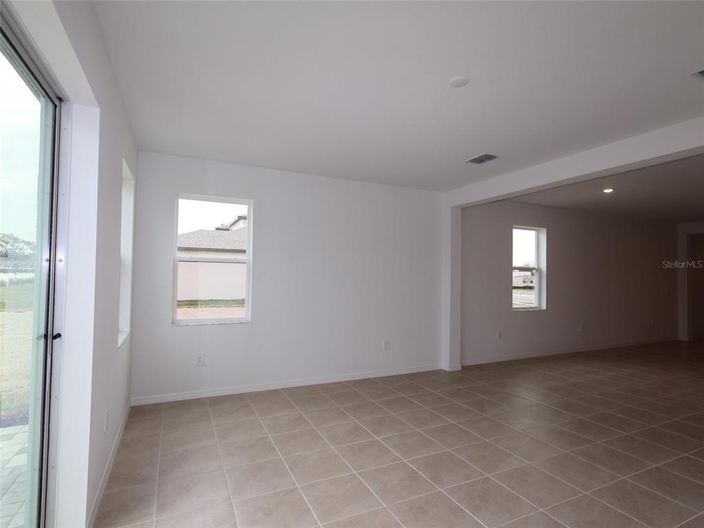 An empty room with beige tile flooring, white walls, and a sliding glass door — 4520 OUTHAUL RUN, PALMETTO, FL