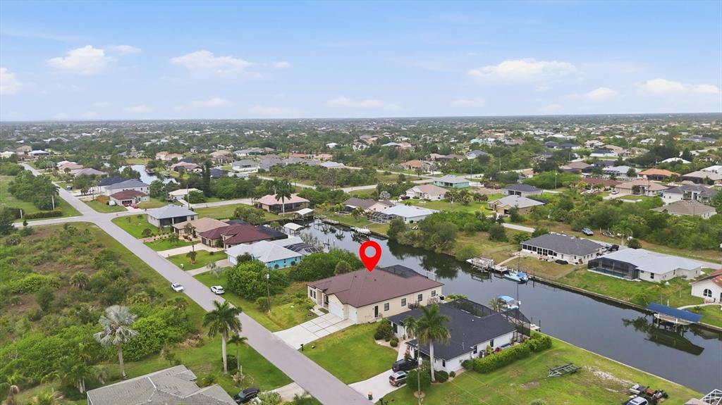 An aerial view shows a residential house with a brown roof located along a canal — 9222 ROSEBUD CIRCLE, PORT CHARLOTTE, FL
