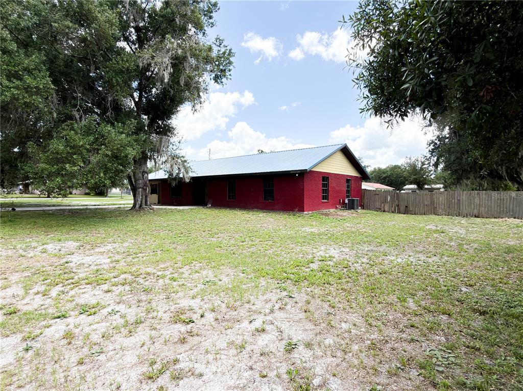 A red brick house with a metal roof stands on a large, grassy lot — 415 3RD STREET W, ZOLFO SPRINGS, FL