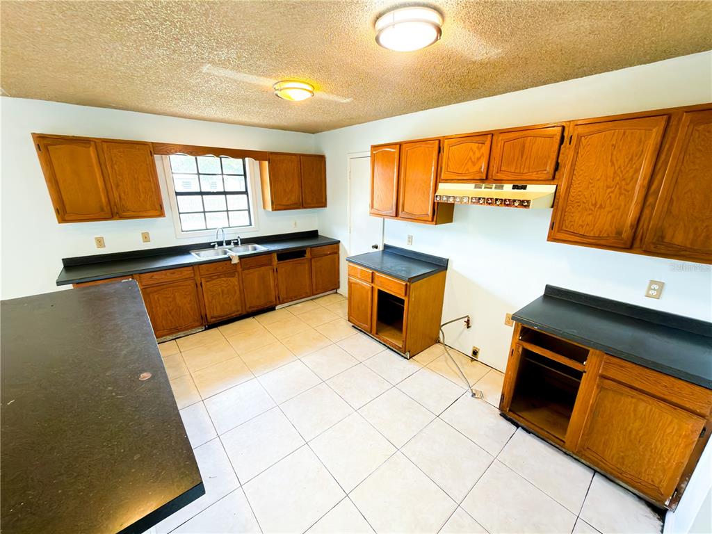 A kitchen with wood cabinets, black countertops, and light-colored floor tiles — 415 3RD STREET W, ZOLFO SPRINGS, FL
