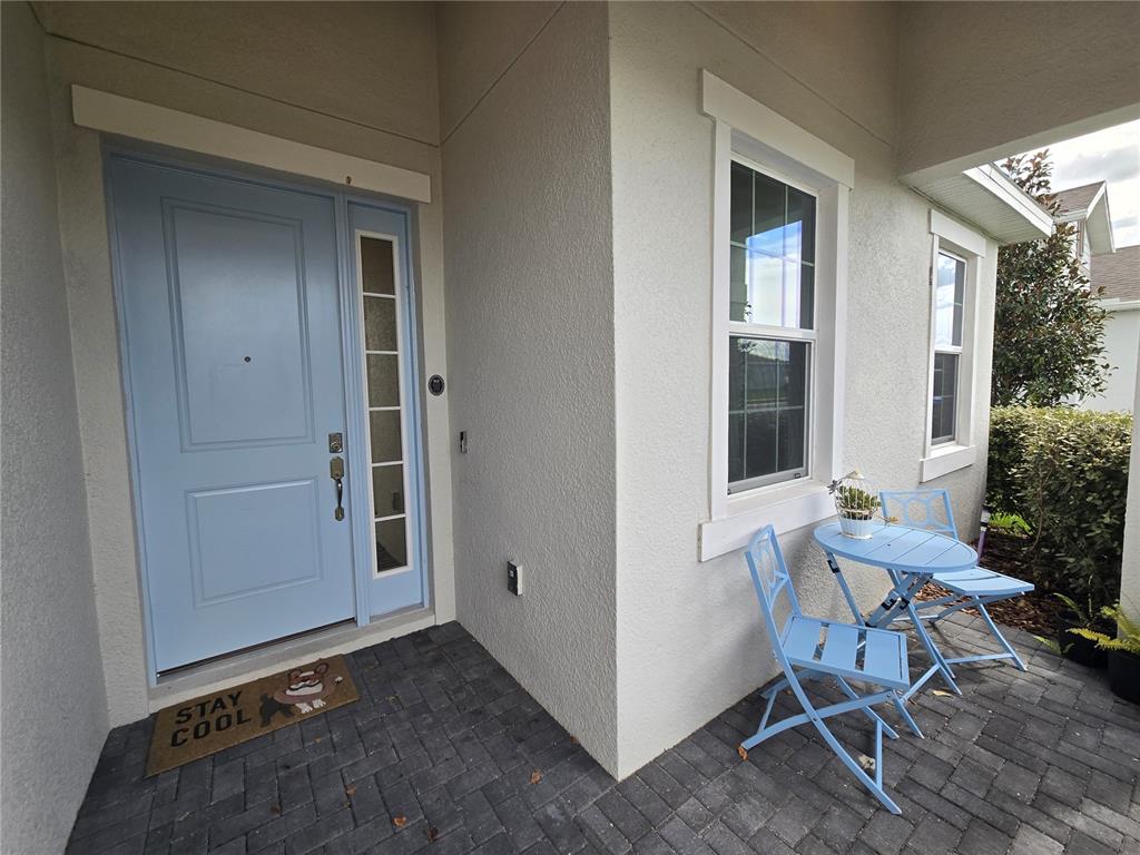 A light blue front door and a small patio set sit on a paved porch — 1225 TUPELO TRAIL, HAINES CITY, FL