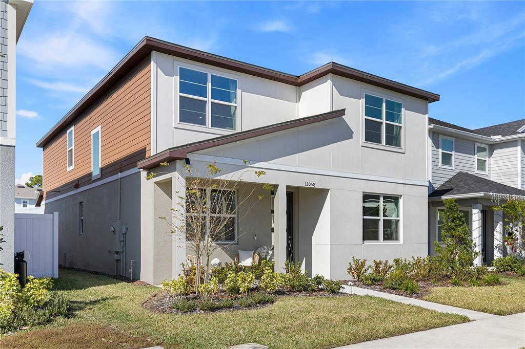 A two-story house with a tan and white exterior features a covered front porch — 13058 PERGOLA AVENUE, ORLANDO, FL