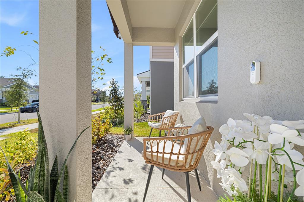 A covered front porch features two wicker chairs, a doorbell camera, and potted plants — 13058 PERGOLA AVENUE, ORLANDO, FL