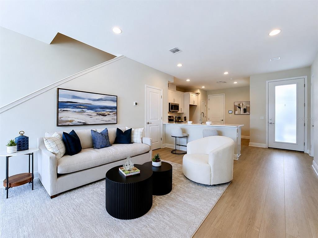 A living room with a sofa, two round coffee tables, and an open kitchen area — 7781 93RD STREET N, SEMINOLE, FL