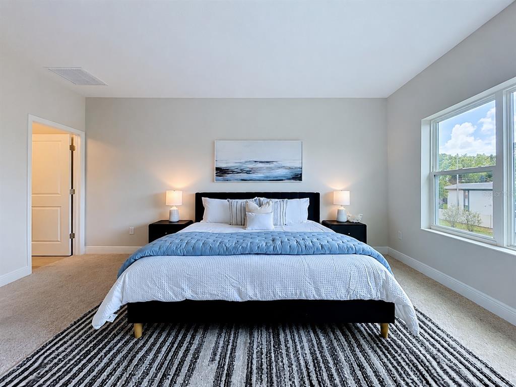 A bedroom features a black bed frame, blue bedding, two nightstands, and a striped rug — 7781 93RD STREET N, SEMINOLE, FL