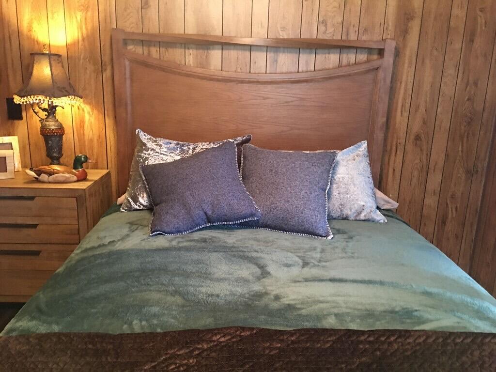 A bedroom features a wooden headboard, a green bedspread, and wood-paneled walls — 1163 20th Street, Okeechobee FL 34974, OKEECHOBEE, FL