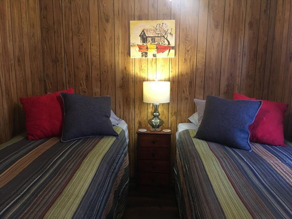 A bedroom features two twin beds with striped bedding and wood-paneled walls — 1163 20th Street, Okeechobee FL 34974, OKEECHOBEE, FL