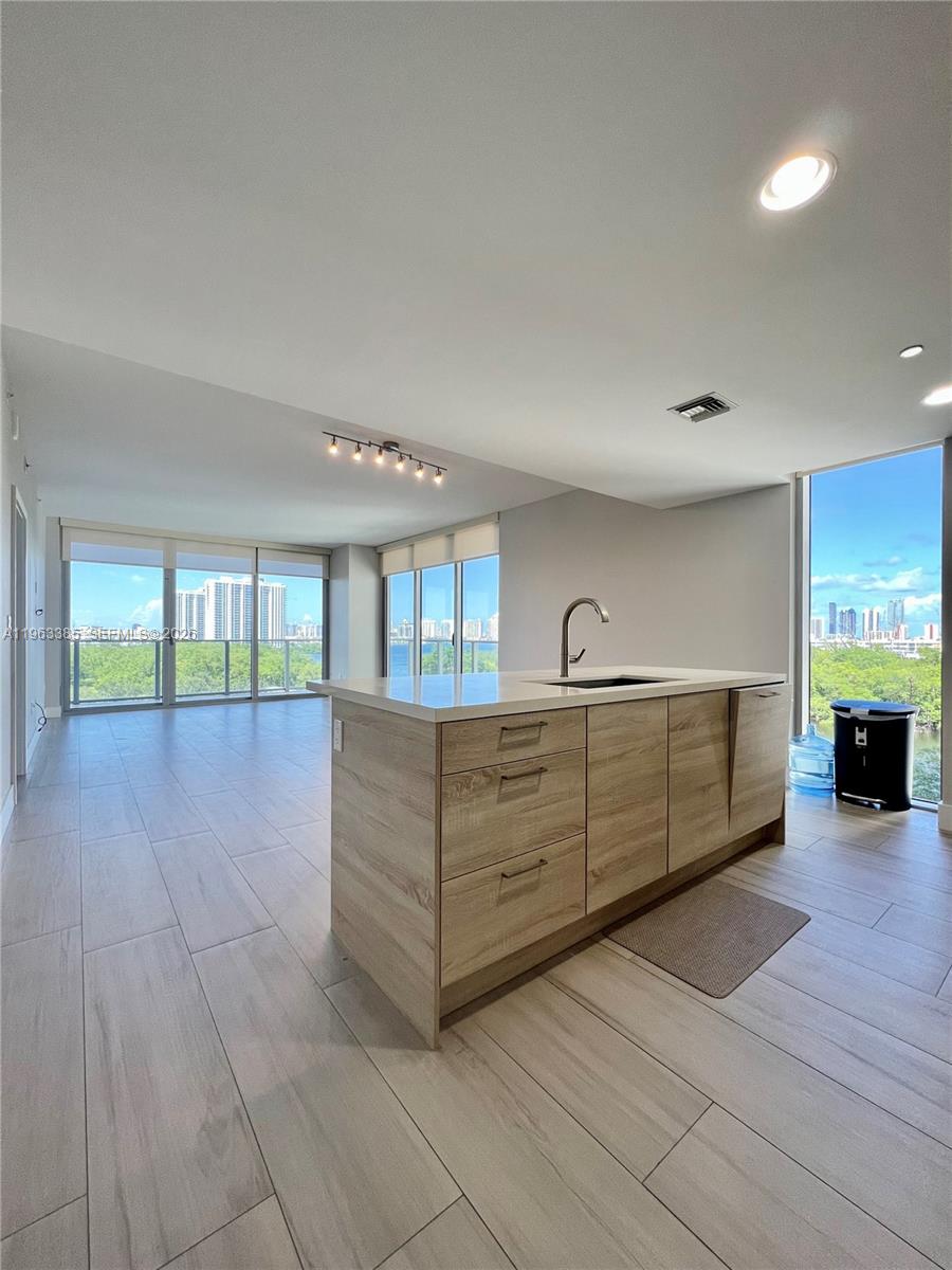 A kitchen island with wood-look cabinets and a white countertop sits in a bright room — 16385 Biscayne Blvd # 607, North Miami Beach FL 33160, NORTH MIAMI BEACH, FL