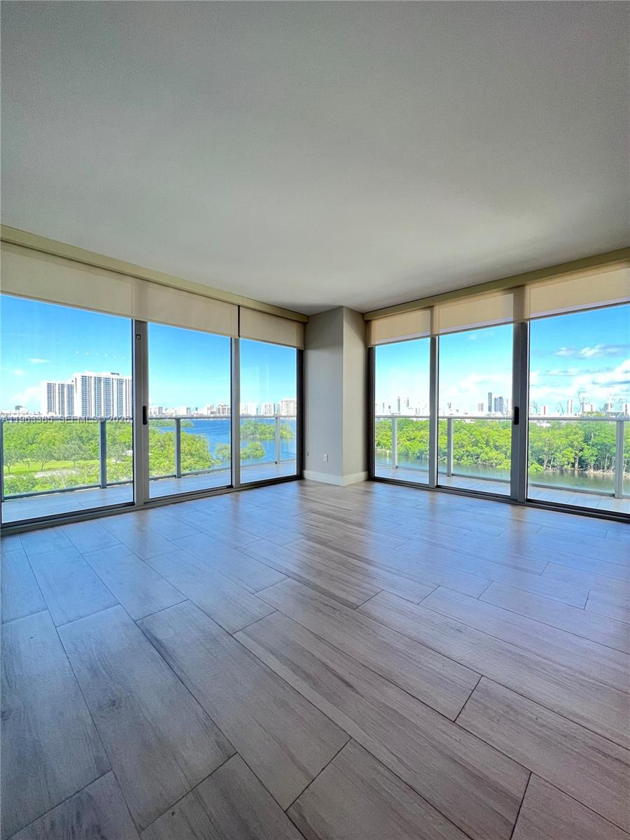 An empty room with light wood-look tile flooring and floor-to-ceiling windows overlooking a waterway — 16385 Biscayne Blvd # 607, North Miami Beach FL 33160, NORTH MIAMI BEACH, FL