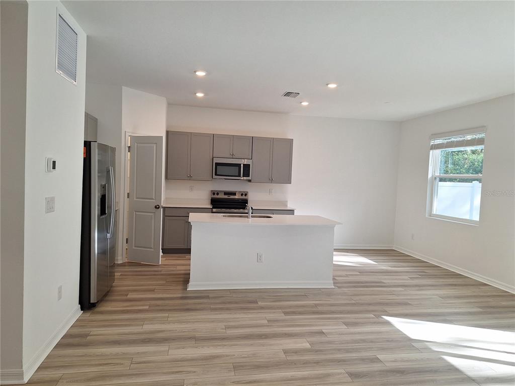 A kitchen with gray cabinets, stainless steel appliances, and a white island on wood flooring — 34916 MULRION DRIVE, ZEPHYRHILLS, FL