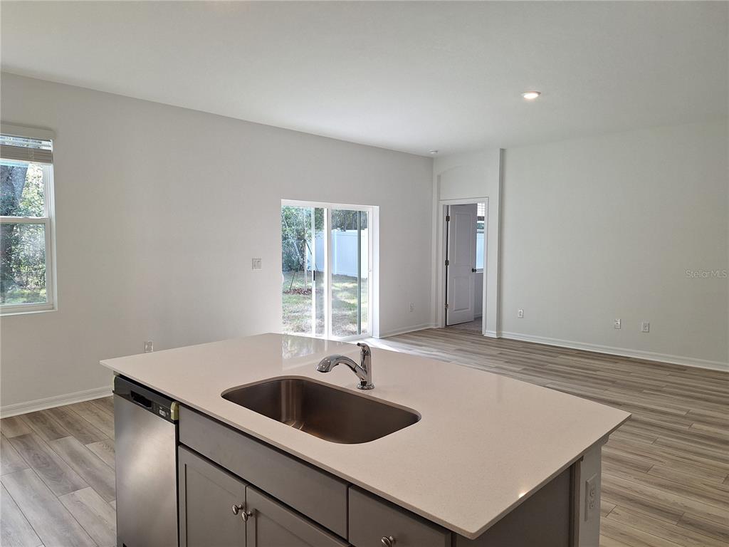 A kitchen island with a stainless steel sink sits in a room with light flooring — 34916 MULRION DRIVE, ZEPHYRHILLS, FL