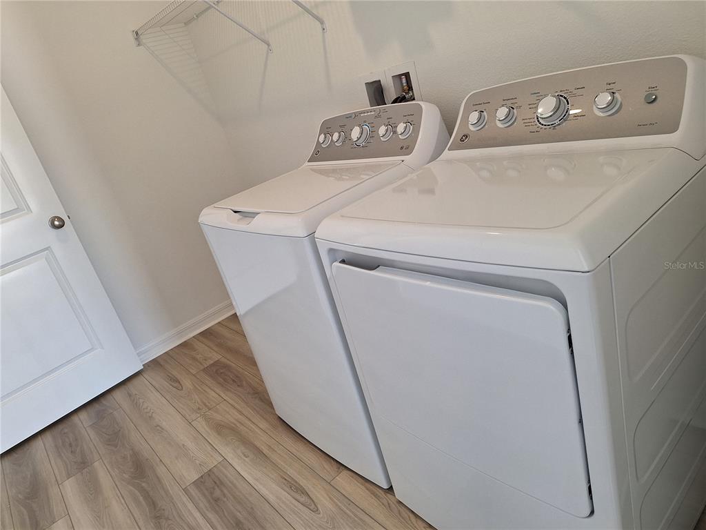 A laundry room features a white washer and dryer set on light wood-look flooring — 34916 MULRION DRIVE, ZEPHYRHILLS, FL