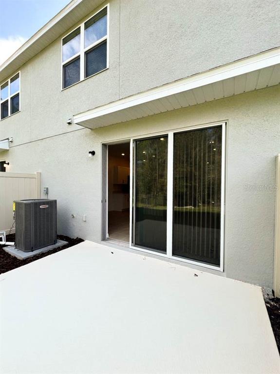 A concrete patio sits outside a sliding glass door next to an outdoor HVAC unit — 3639 DAVENPORT CREEK COURT, KISSIMMEE, FL