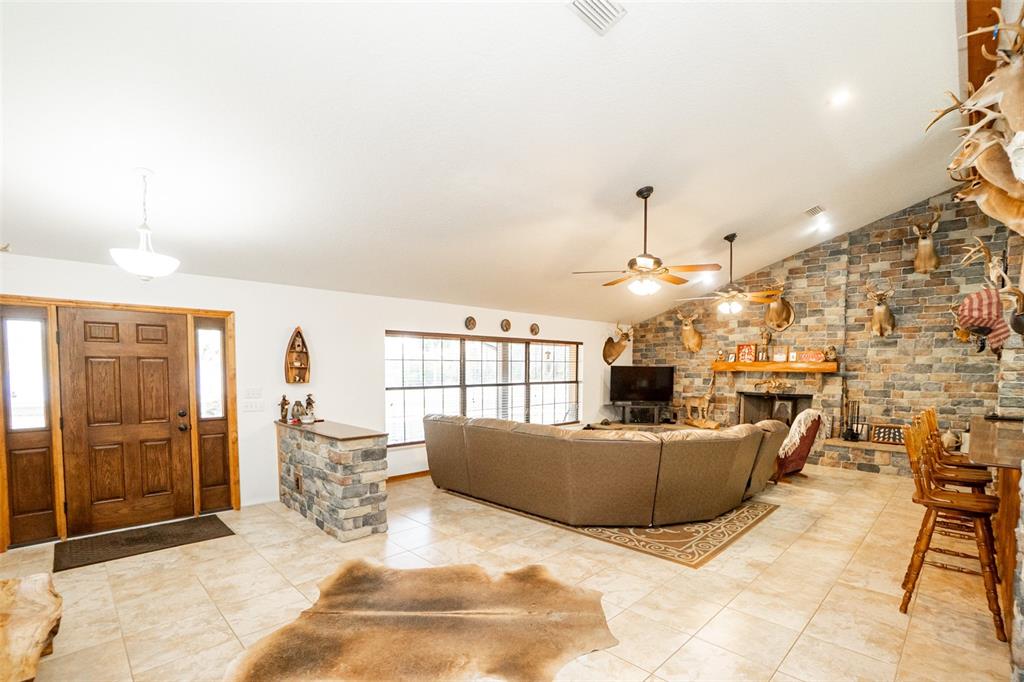A living room features a stone fireplace, a large sectional sofa, and taxidermy mounts — 8600 NE 147TH AVENUE ROAD, SILVER SPRINGS, FL