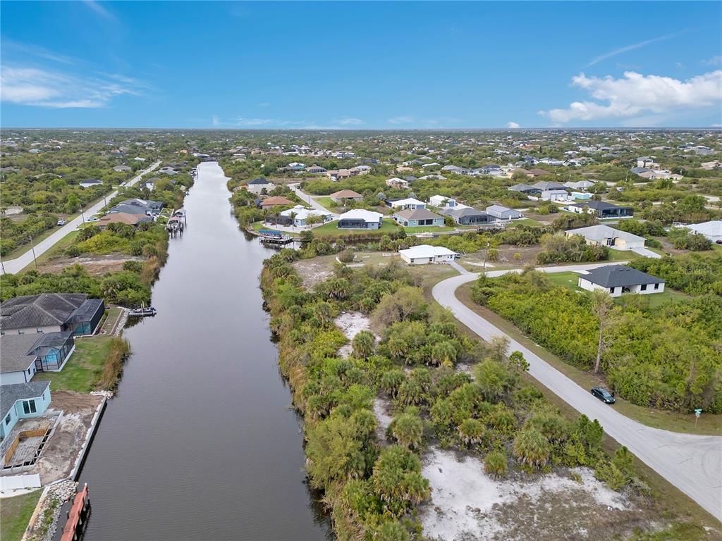 An aerial view shows a canal winding through a residential neighborhood with scattered houses — 14246 FORT WORTH CIRCLE, PORT CHARLOTTE, FL