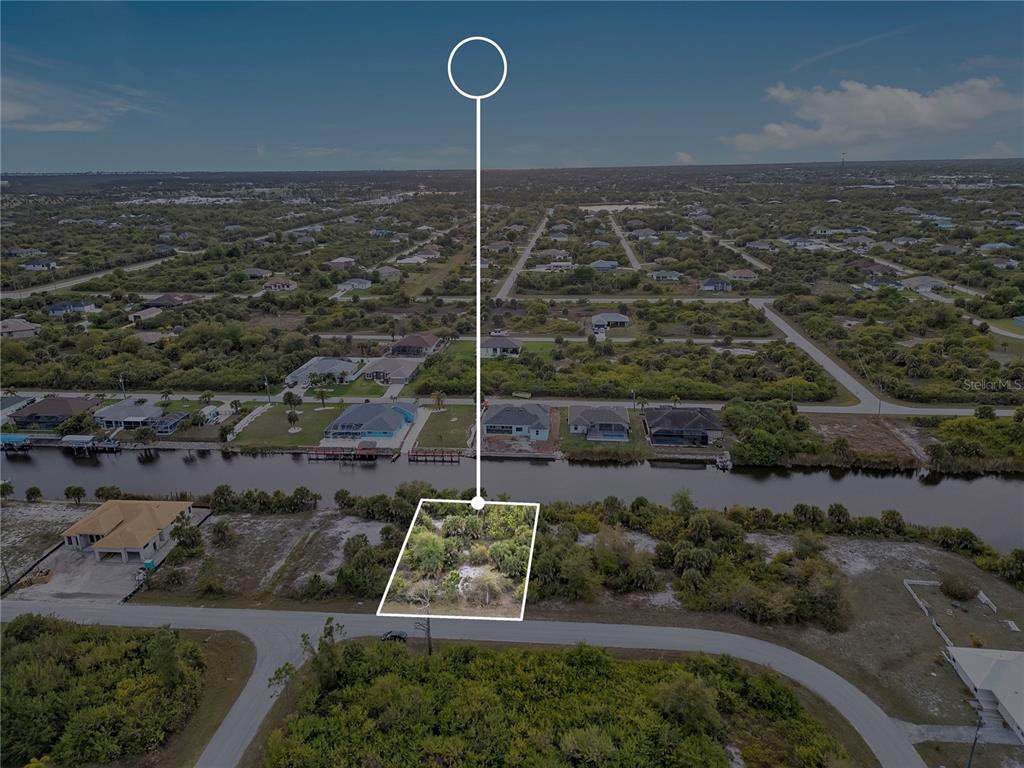An aerial view shows a vacant, wooded waterfront lot outlined in white — 14246 FORT WORTH CIRCLE, PORT CHARLOTTE, FL