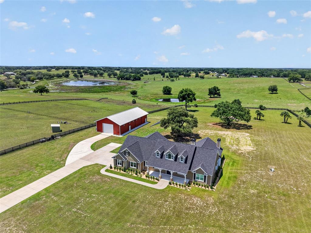 An aerial view shows a house and a red barn on a large rural property — 5496 NANTAHALA LANE, LADY LAKE, FL