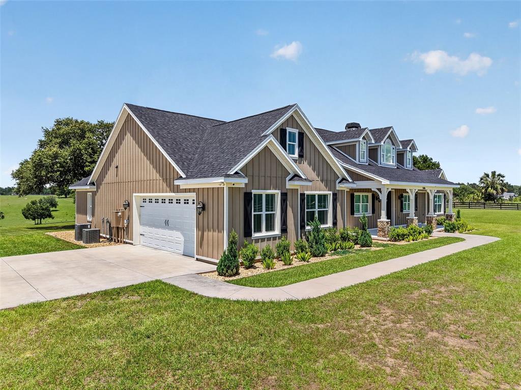 A tan house with board-and-batten siding, a white garage door, and a covered front porch — 5496 NANTAHALA LANE, LADY LAKE, FL