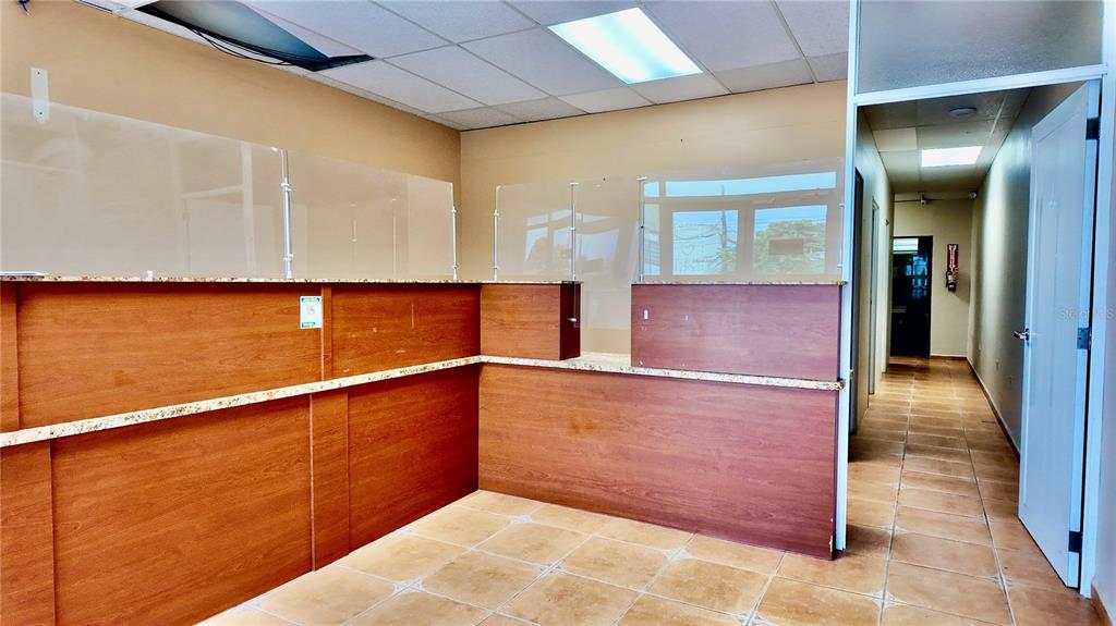 A reception area features a wood-paneled counter with a glass partition and tile flooring — 115 C. MARGINAL, RINCON, PR