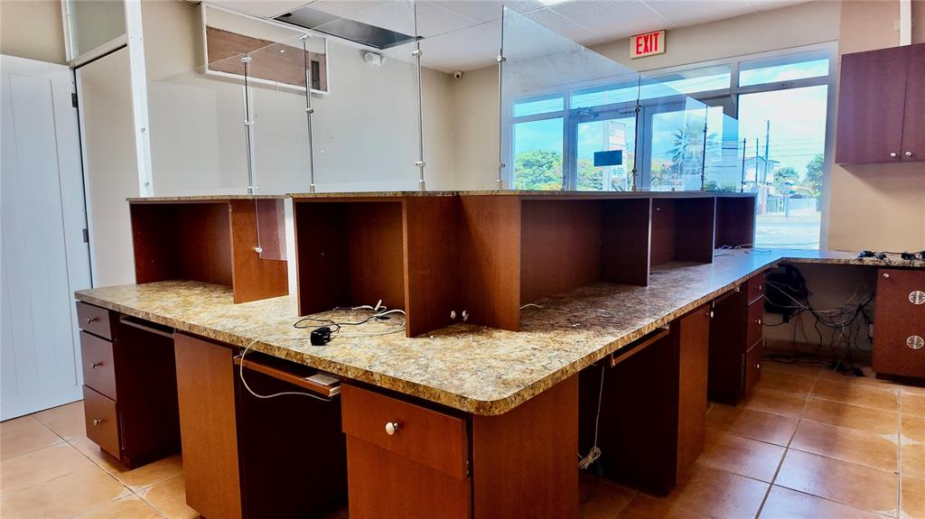 An office space features a large, multi-station wooden desk with granite countertops and glass partitions — 115 C. MARGINAL, RINCON, PR