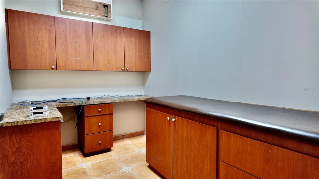 A small medical exam room features wood cabinetry, a granite countertop, and a padded table — 115 C. MARGINAL, RINCON, PR