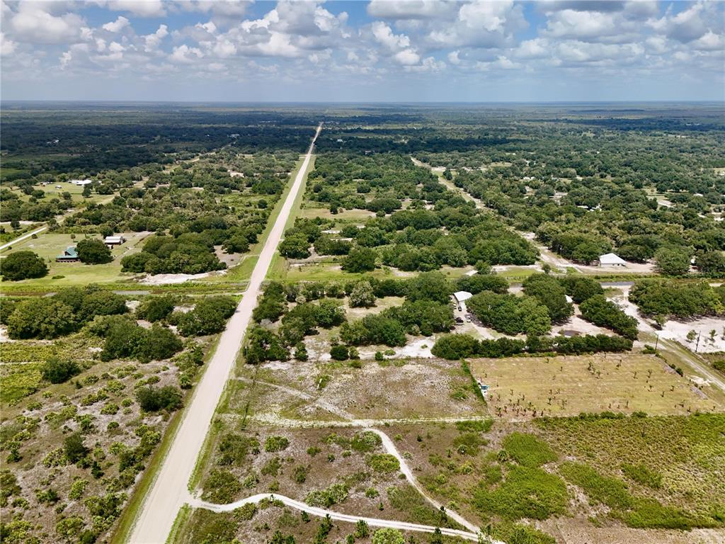 An aerial view shows a long, straight road cutting through a rural, wooded landscape — 18277 NW 304TH STREET, OKEECHOBEE, FL