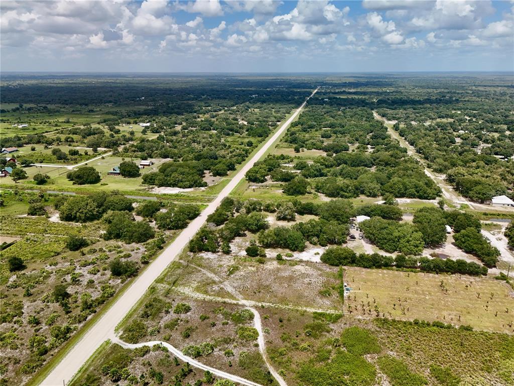 An aerial view shows a long, straight road cutting through a rural, wooded landscape — 18277 NW 304TH STREET, OKEECHOBEE, FL