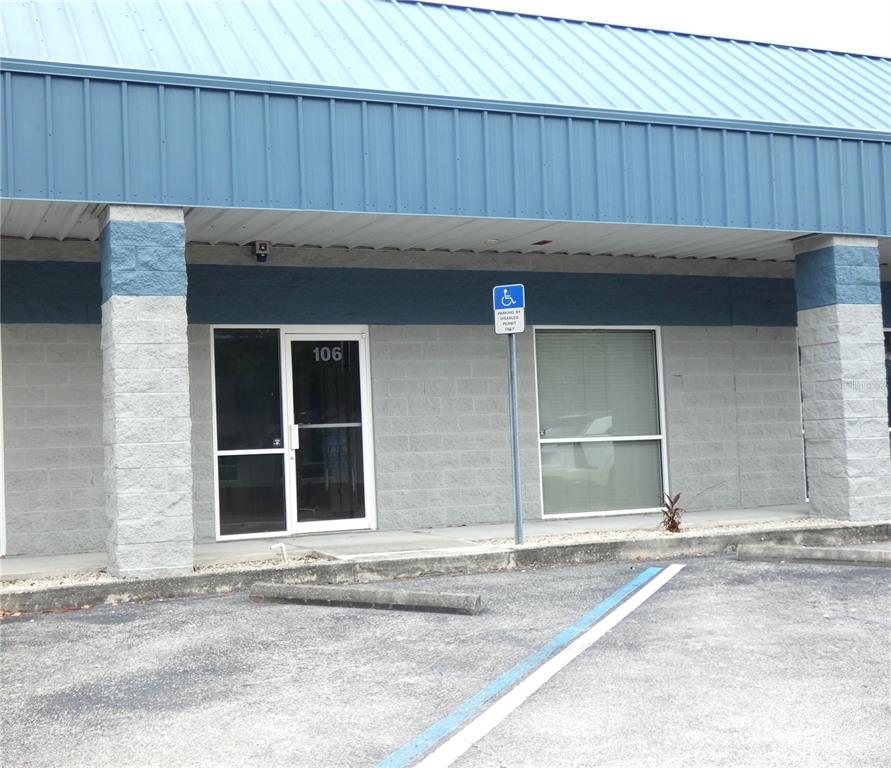 The exterior of a commercial building features a blue metal roof and gray block walls — 1882 PORTER LAKE DRIVE UNIT 106, SARASOTA, FL